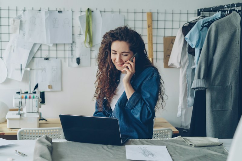 Une créatrice au téléphone travaille sur son ordinateur portable dans son atelier