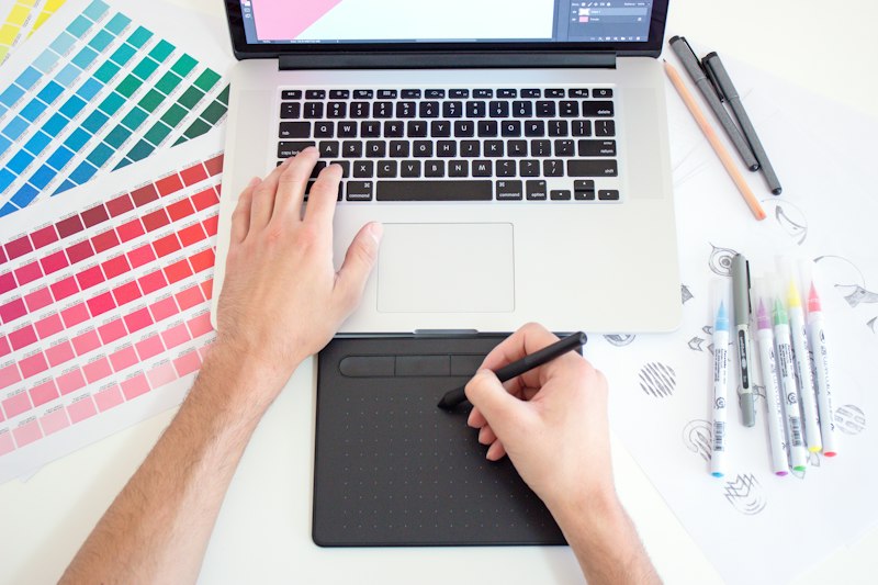 Une designer travaille sur des nuanciers de couleurs et une tablette graphique