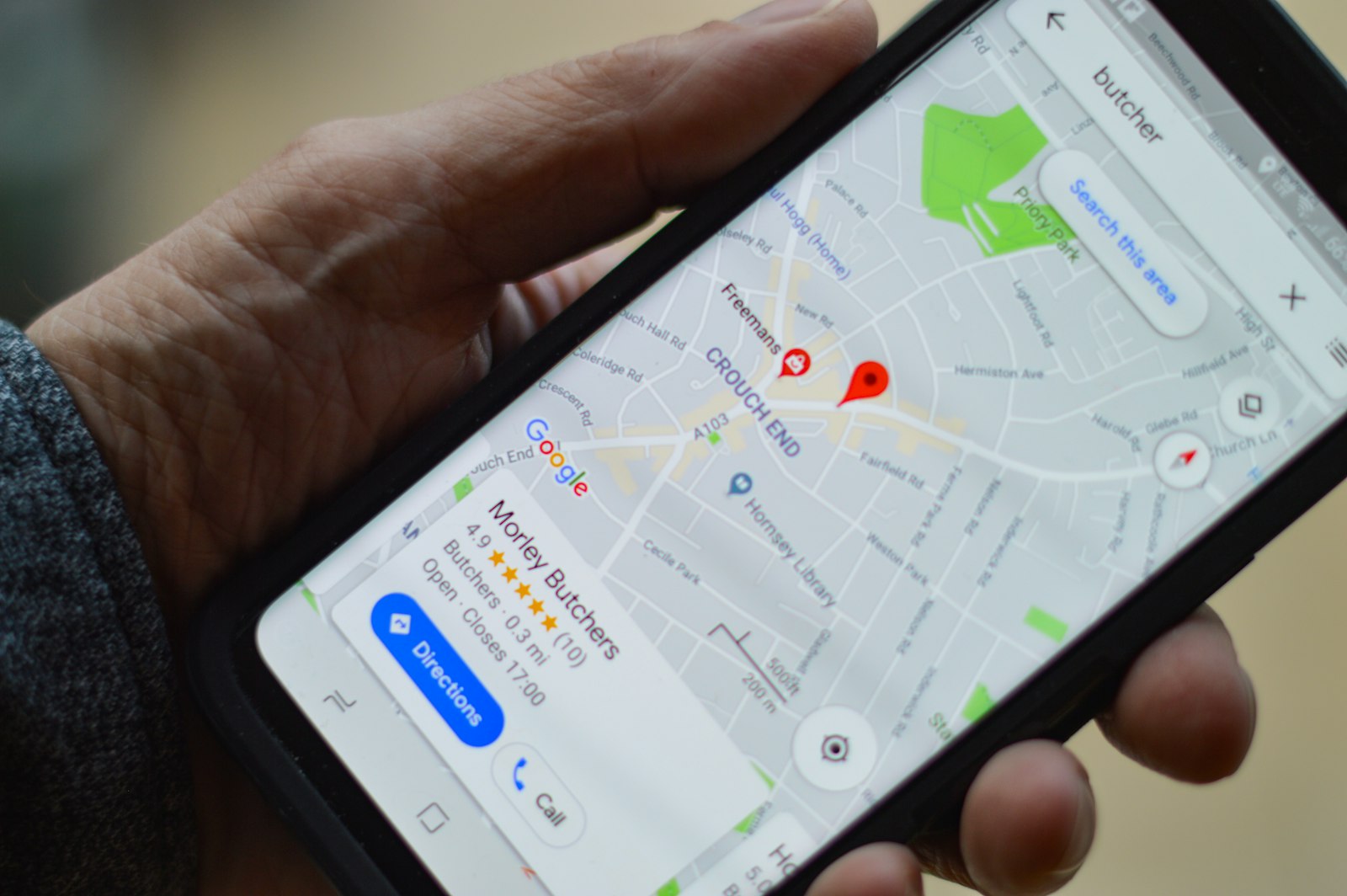 Une main tient un téléphone affichant une fiche d’établissement sur Google Maps